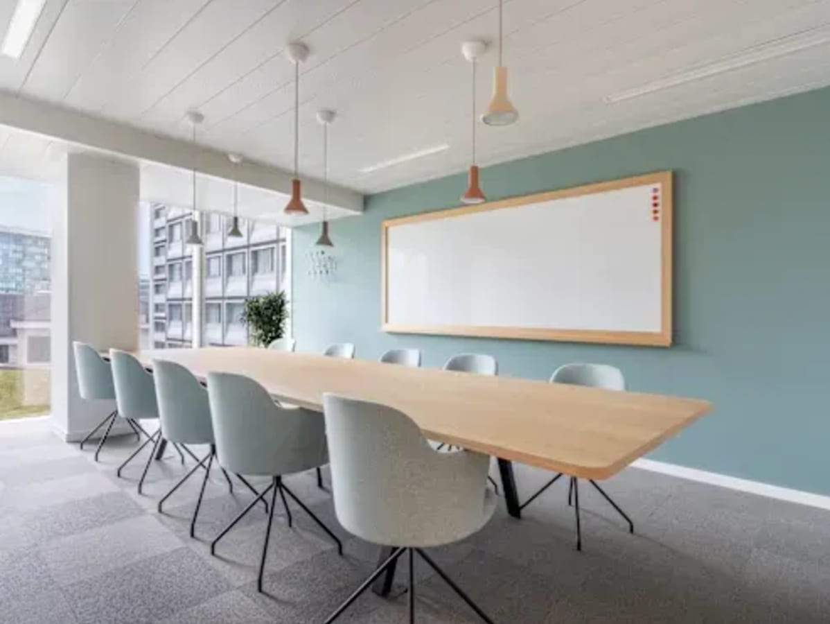 Modern conference room with natural light, sleek chairs, and large whiteboard. Perfect for meetings.