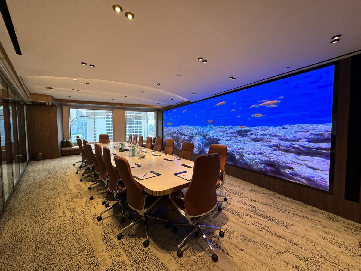 Elegant meeting room with a large digital screen and sleek leather chairs, perfect for dynamic presentations.