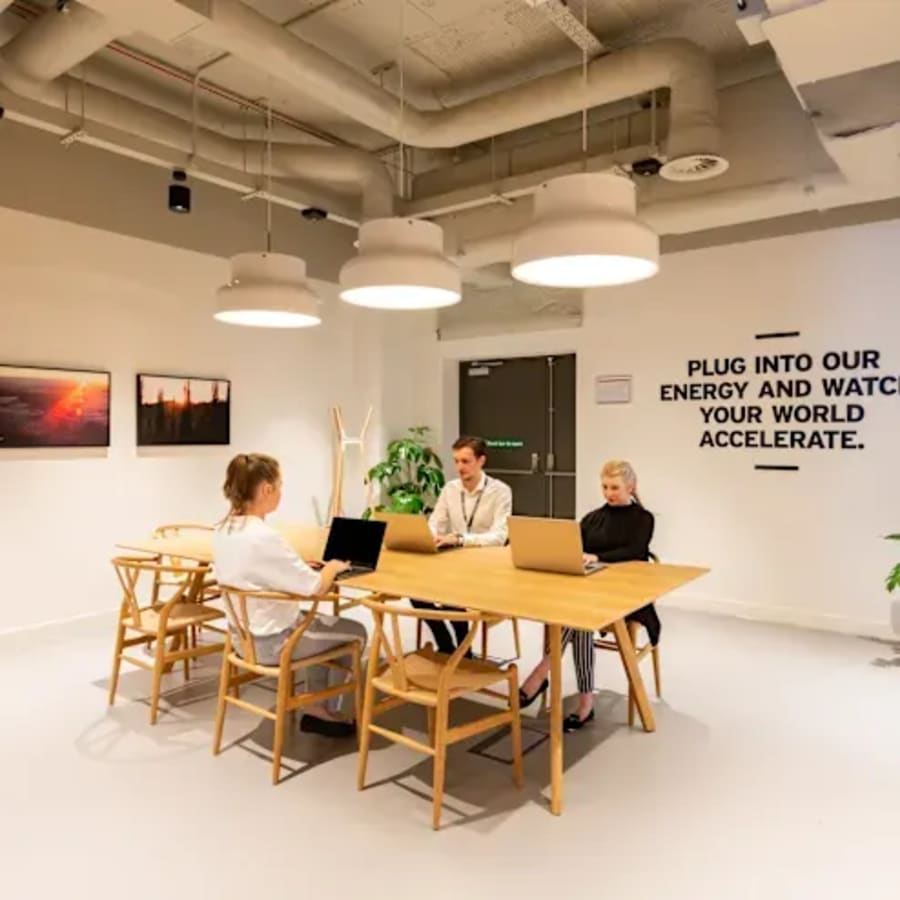 Modern coworking space with open seating, vibrant lighting, and motivational decor.