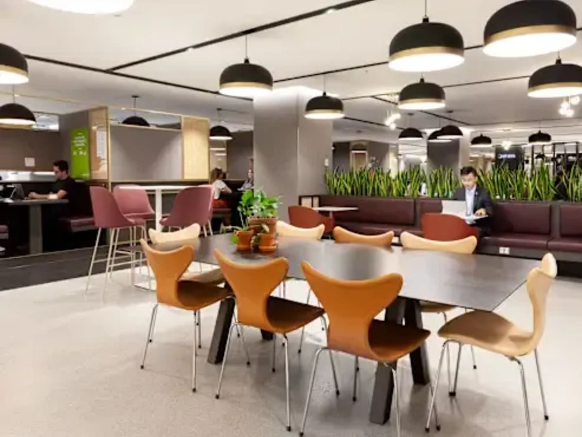 Modern coworking space with stylish seating, lush greenery, and ample lighting. Perfect for collaboration.