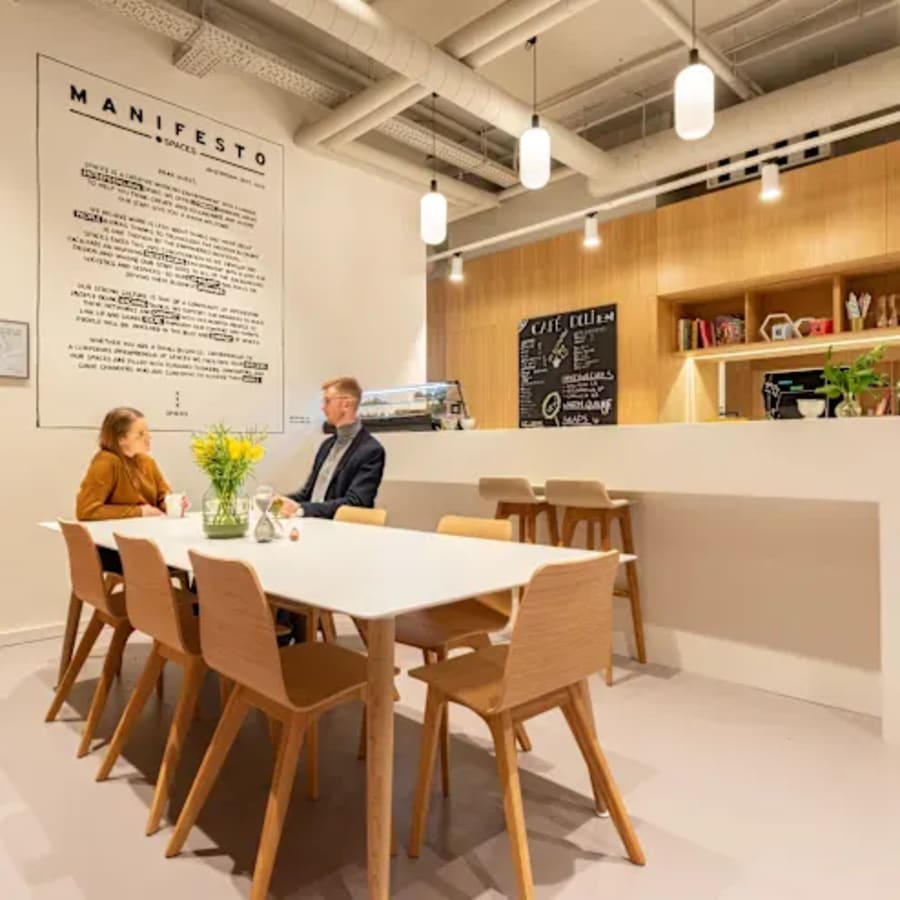 Modern coworking space with communal table and cozy cafe area in Dubai Media City.