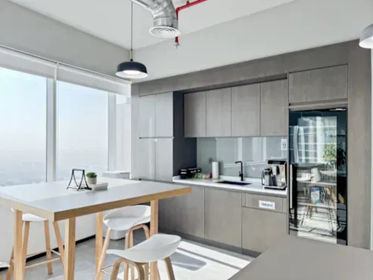 Bright, modern kitchenette with ample natural light, sleek cabinetry, and a communal table. Perfect for collaboration.