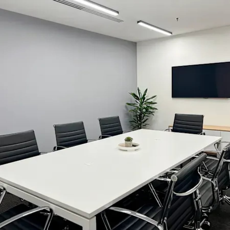 Modern meeting room with sleek seating, minimalist decor, and a large screen for presentations.