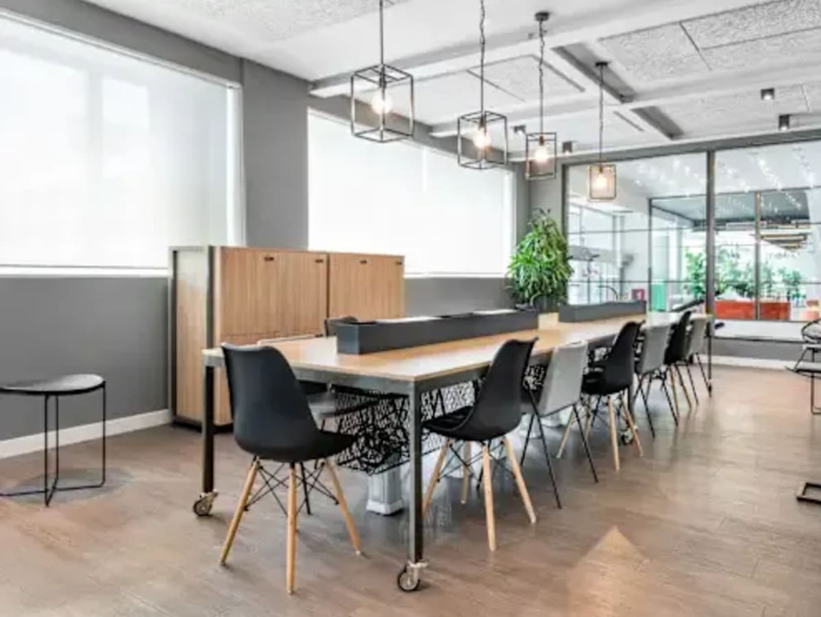 Modern coworking space with sleek furniture, ample natural light, and stylish lighting.