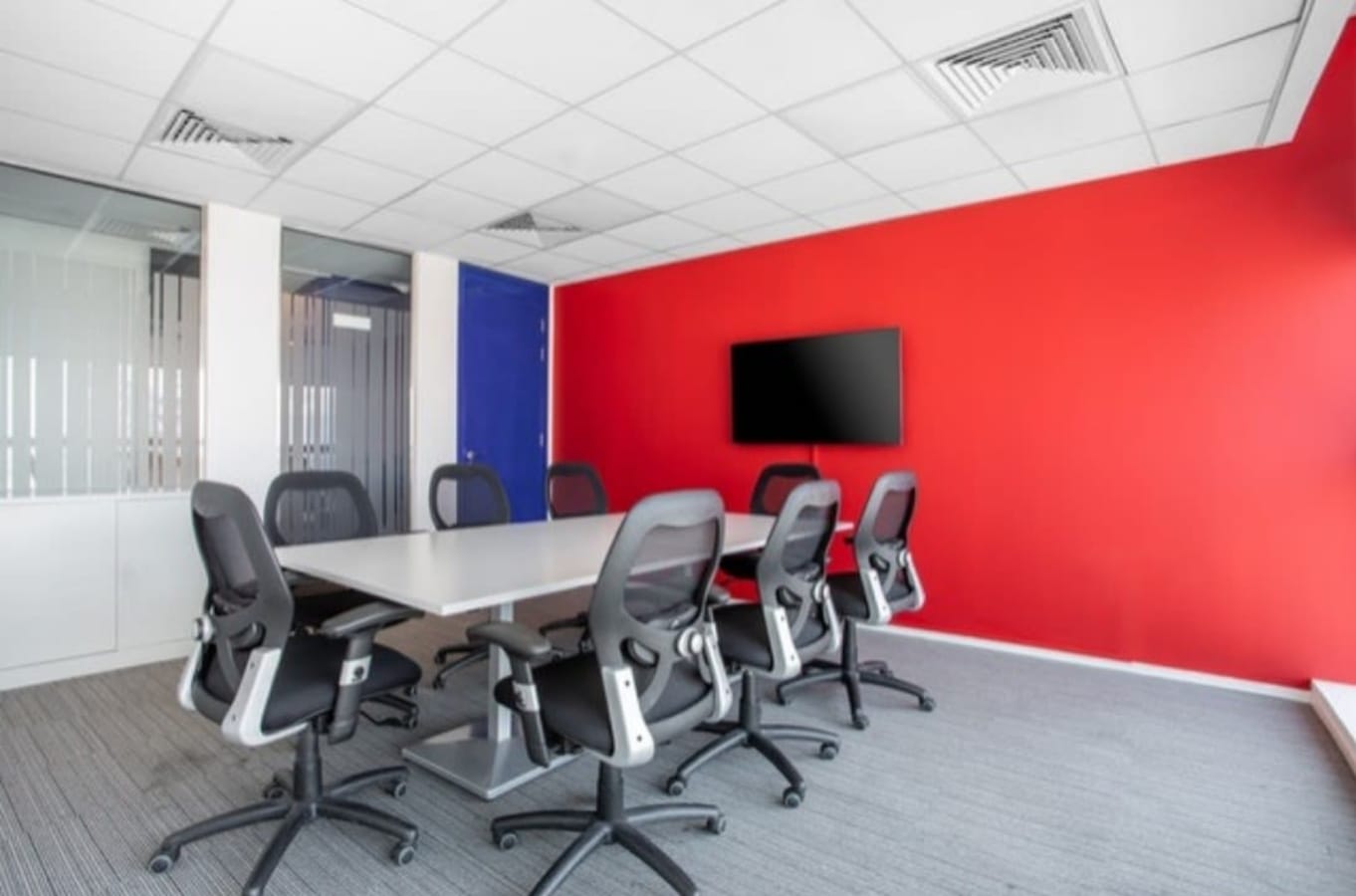 Vibrant meeting room with ergonomic chairs and a smart screen, ideal for dynamic collaborations.