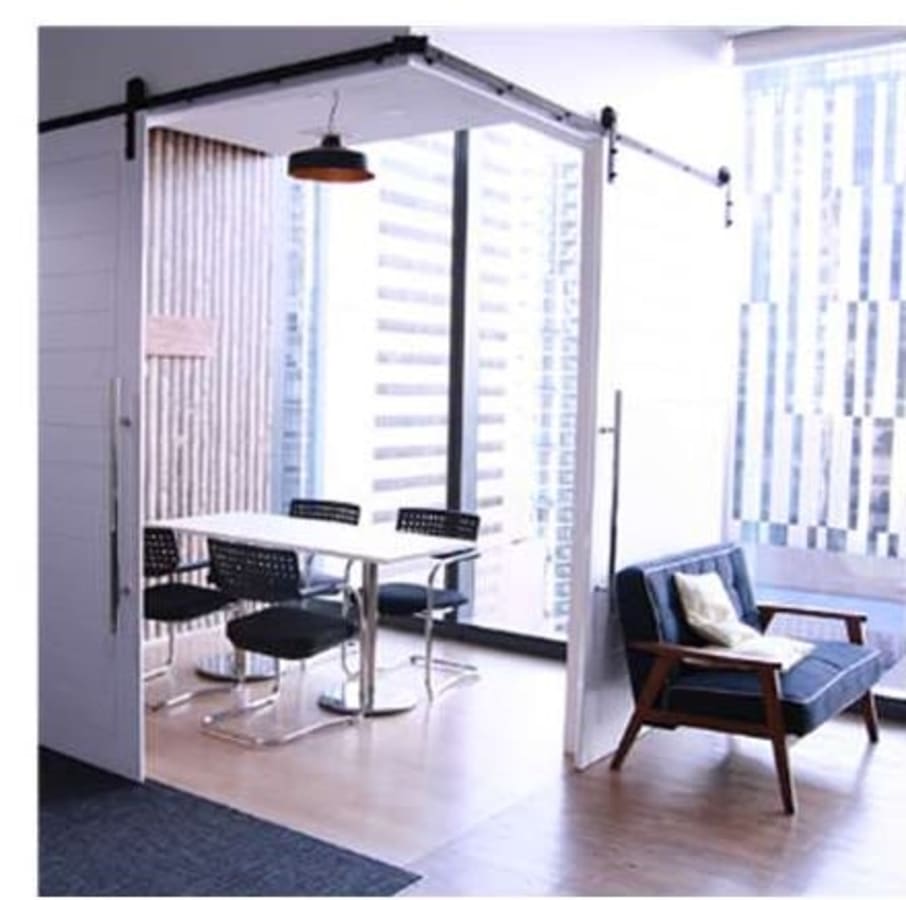 Bright, modern space with a meeting table, cozy seating, and cityscape views. Perfect for collaboration.