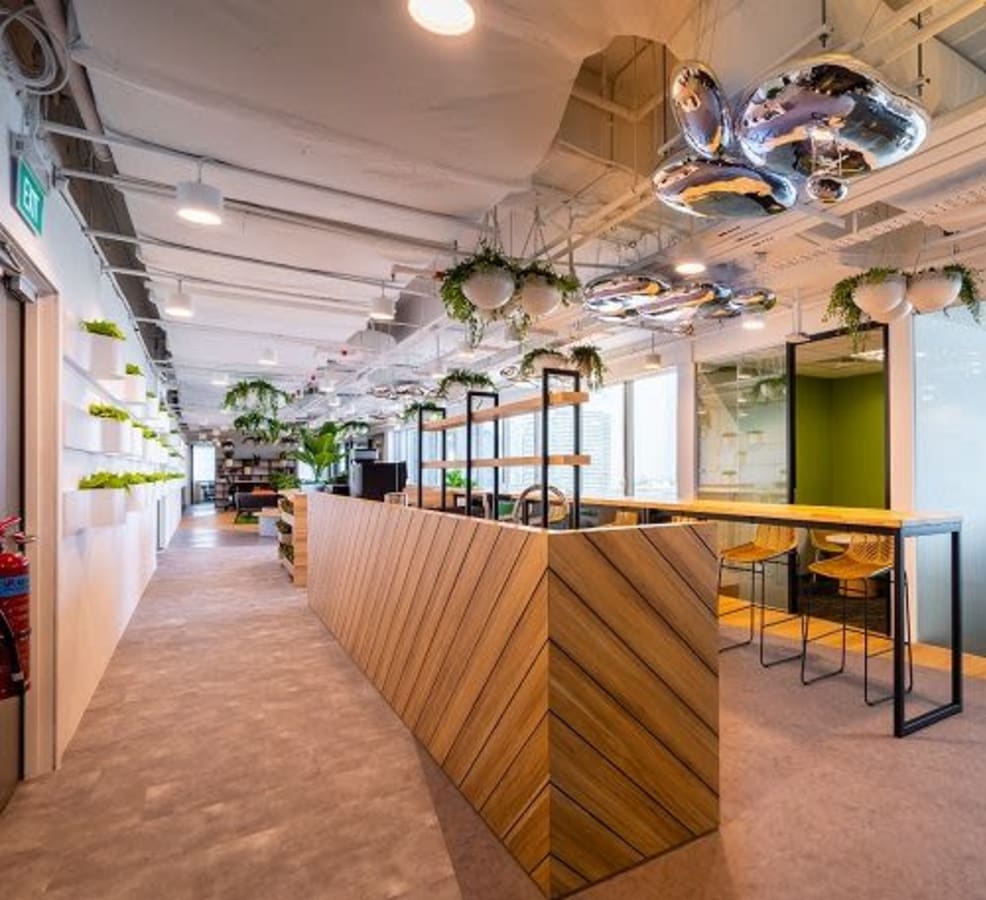 Modern coworking space with stylish seating, vibrant greenery, and ample natural light.