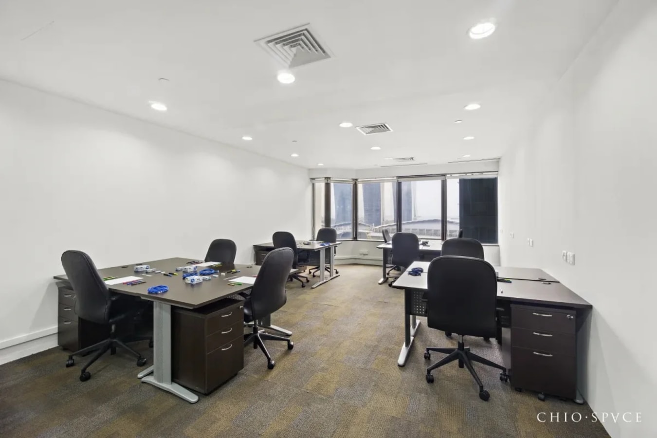 Spacious coworking area with modern desks, ergonomic chairs, and expansive city views.
