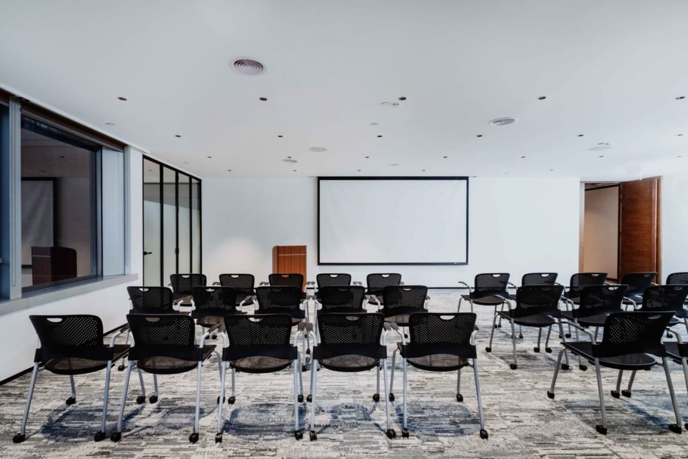 Modern seminar room with seating and projector. Ideal for presentations and workshops.