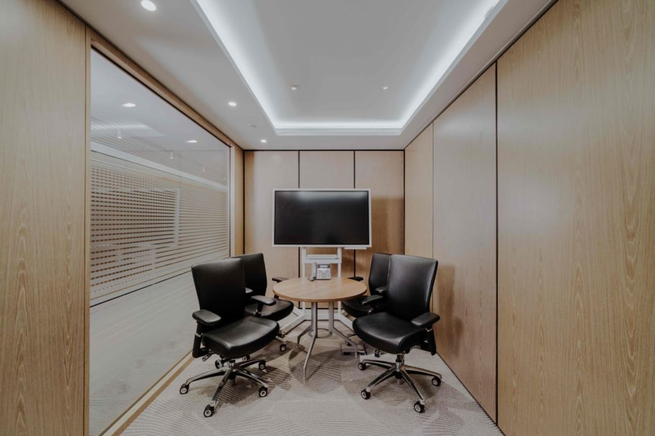 Compact meeting room with modern chairs and a screen, perfect for team collaborations.