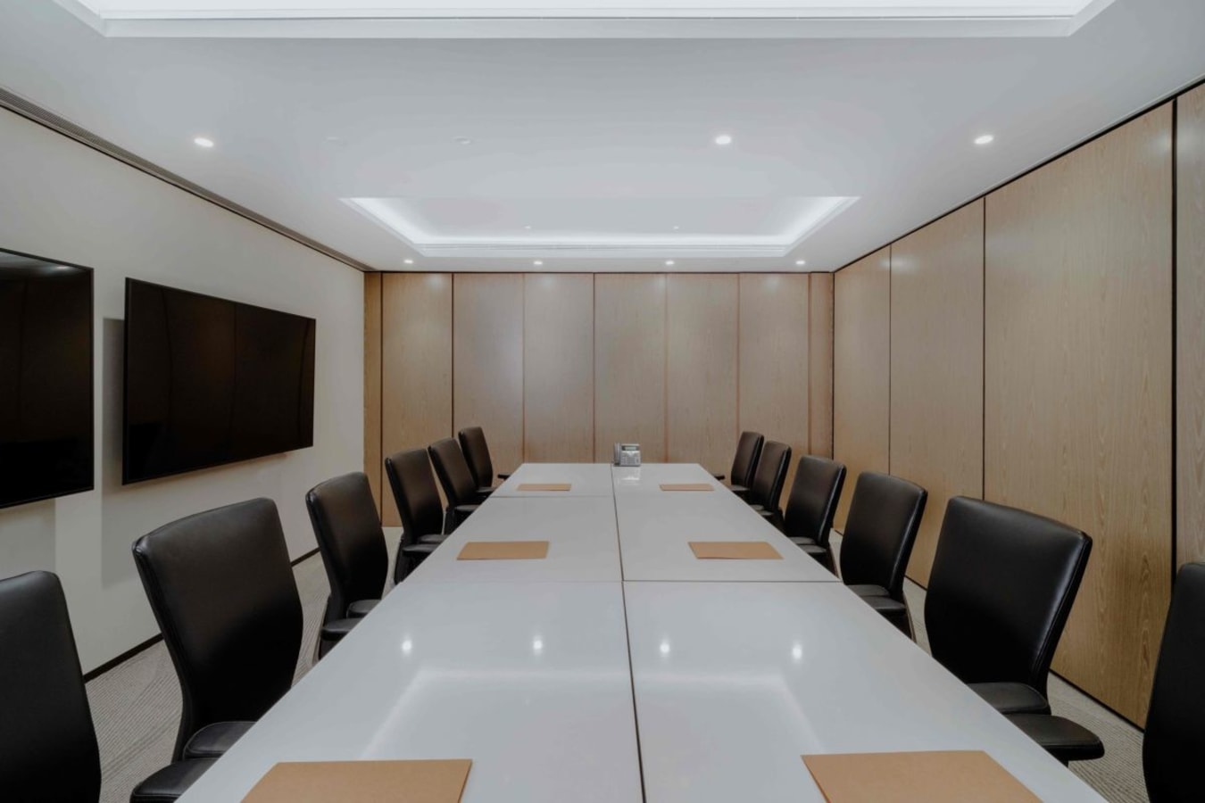 Sleek conference room with modern seating, dual screens, and bright lighting. Ideal for meetings.