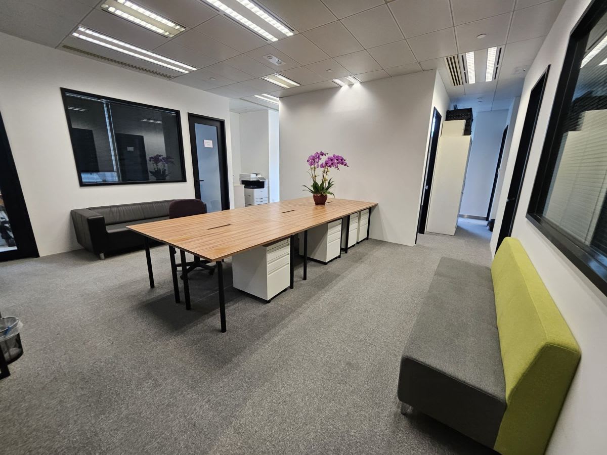 Modern coworking space with natural light, spacious desks, and comfortable seating.