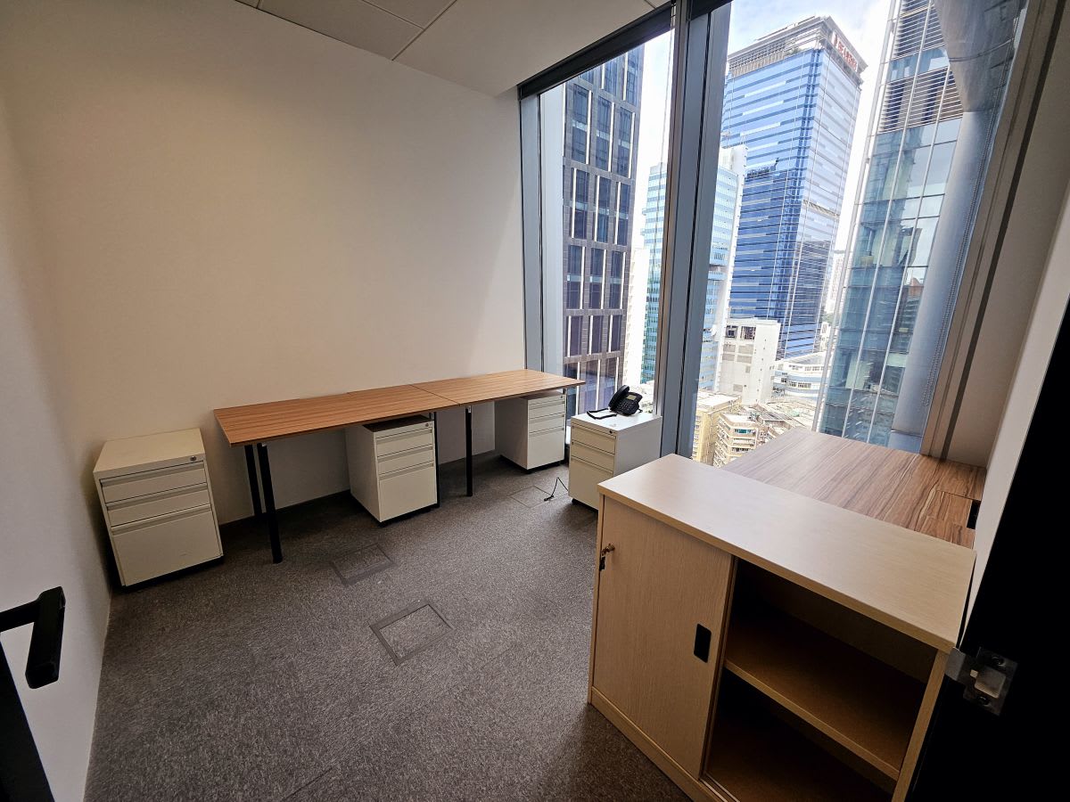 Bright coworking space with a city view, featuring modern desks and ample storage.