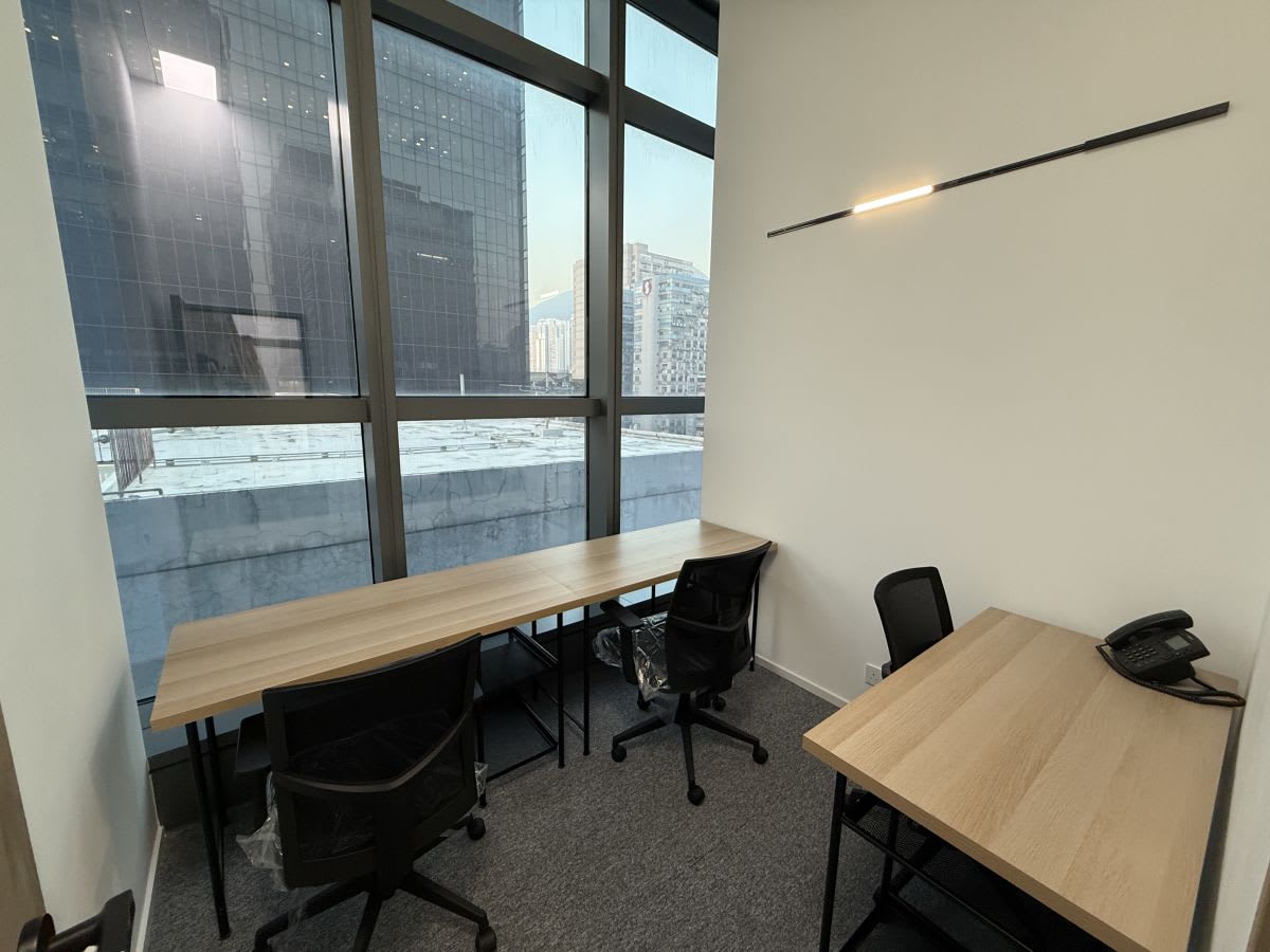 Bright coworking space with large windows, modern furniture, and city views.