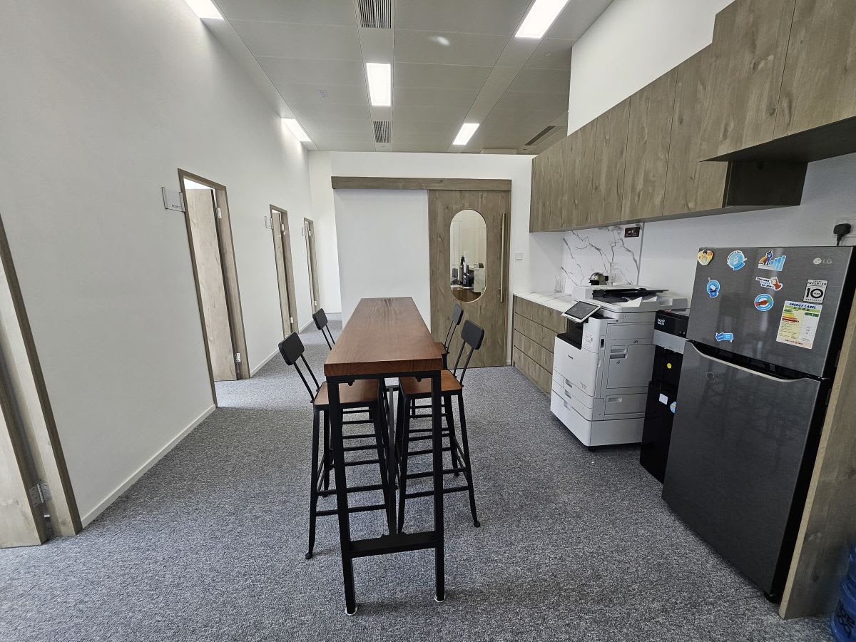 Modern coworking space with communal table, cabinetry, and essential appliances.