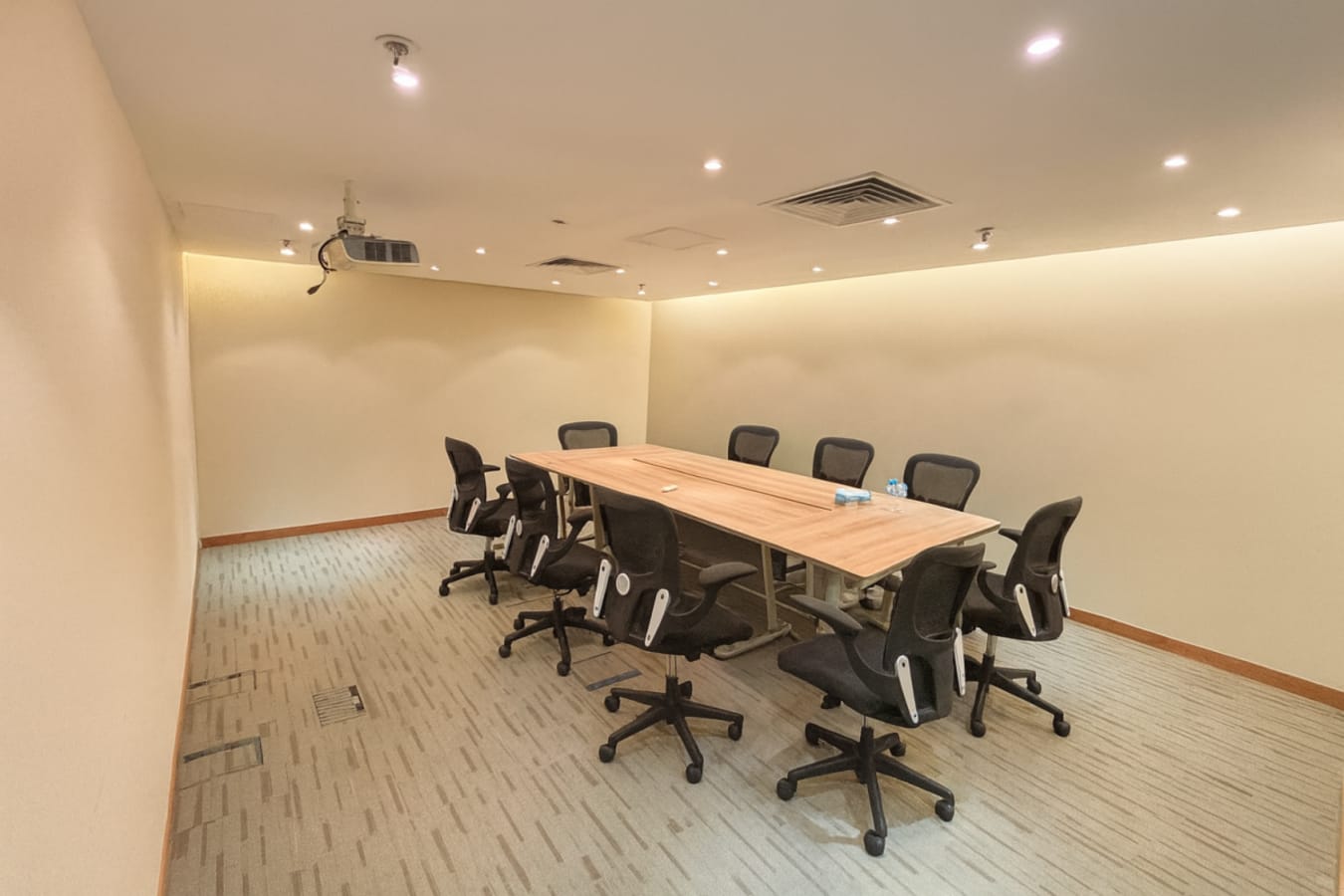 Modern conference room with ergonomic chairs and ceiling projector, ideal for meetings.