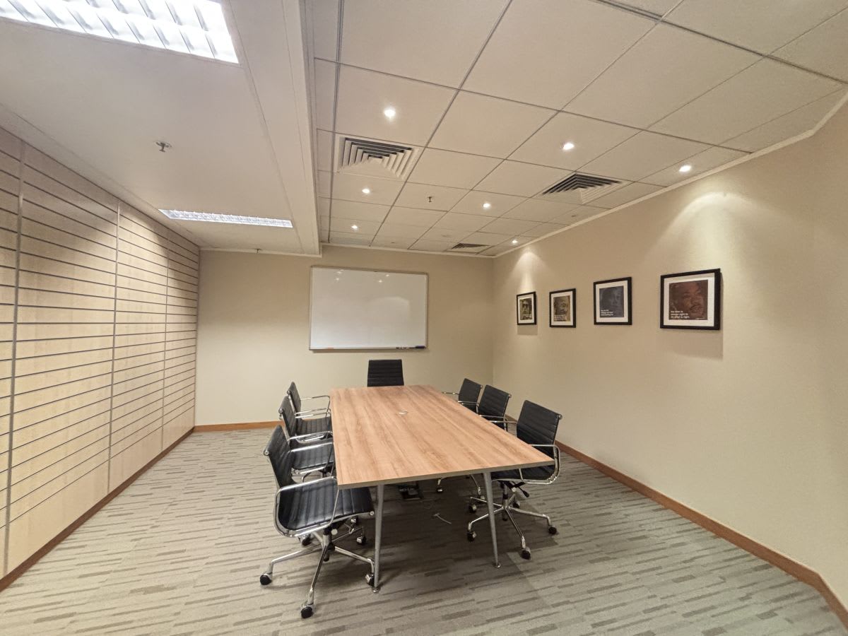Modern conference room with sleek chairs, wooden table, and ample lighting. Ideal for meetings.