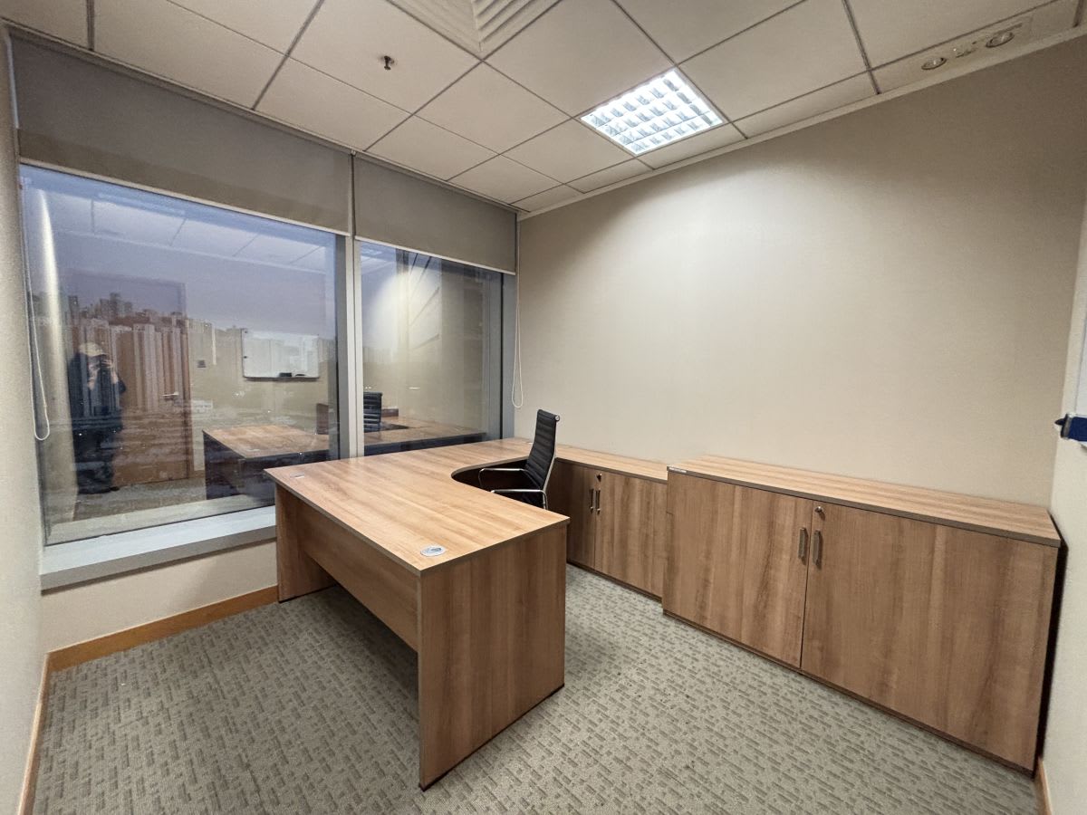 Bright private office with a spacious desk, ample storage, and a large window view.