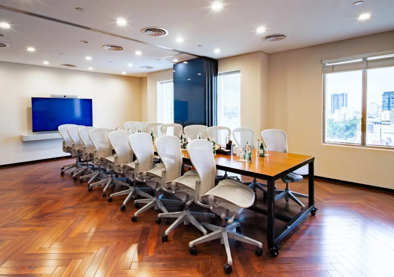 Elegant conference room with modern seating, large screen, and abundant natural light.