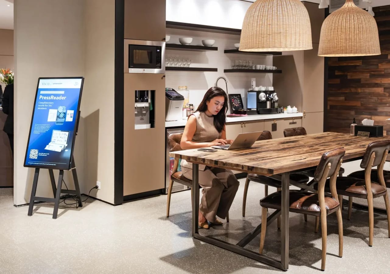 Modern coworking space with cozy seating, coffee bar, and warm lighting for a productive workday.