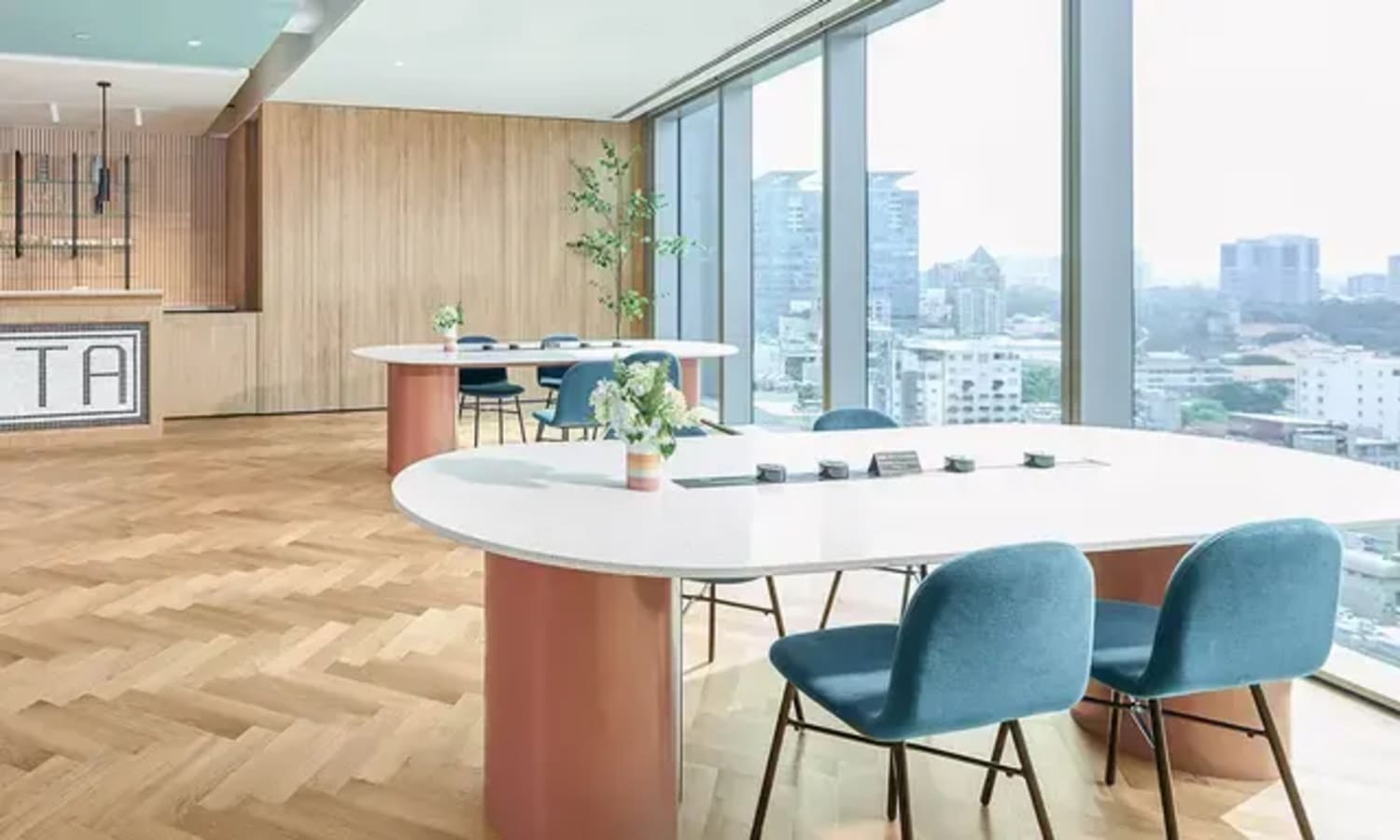 Bright coworking space with panoramic city views, elegant furnishings, and natural light.