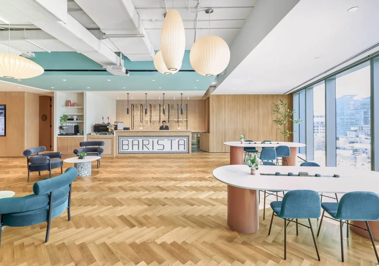 Stylish coworking space with natural light, modern seating, and an inviting barista area.