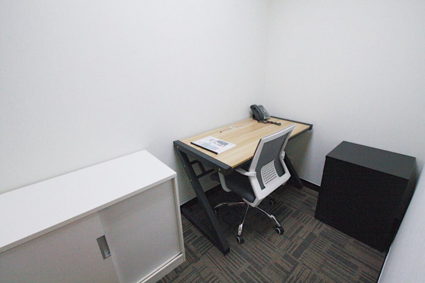 Compact coworking space on Mody Road, featuring a minimalist desk, chair, and ample storage.