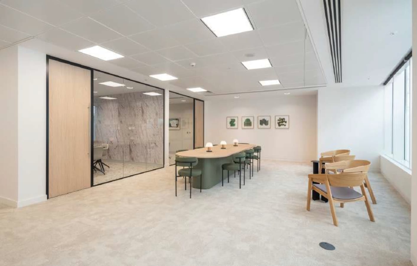Spacious coworking area with modern furniture, glass walls, and ample natural light.
