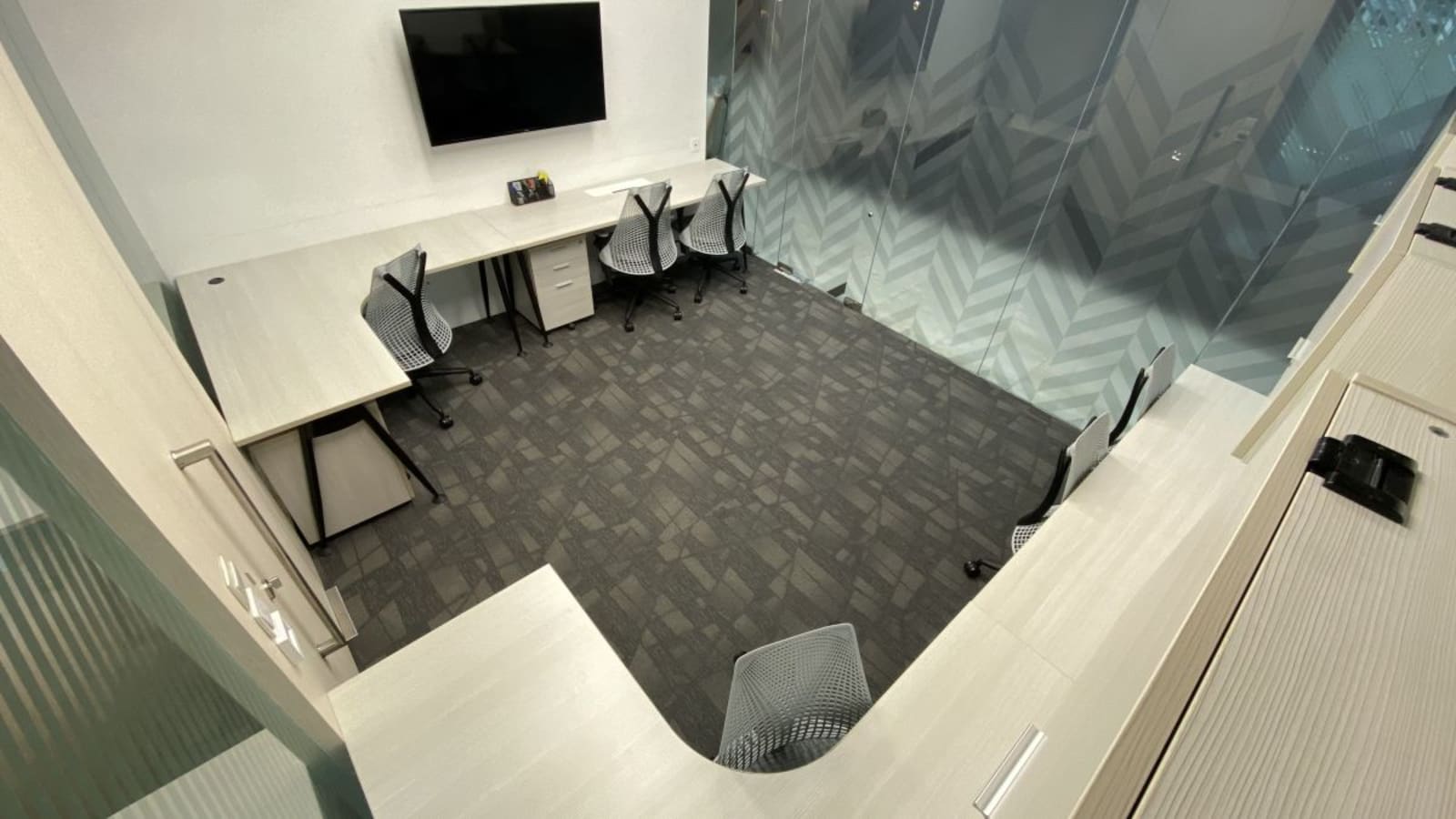 Modern workspace with ergonomic chairs, sleek desks, and a large screen. Ideal for collaboration.