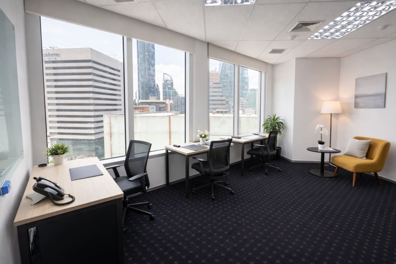 Bright coworking space in Pathumwan with city views, modern desks, cozy seating, and natural light.