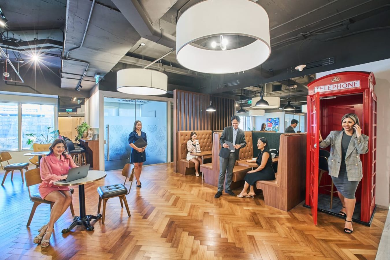 Vibrant coworking space with varied seating, stylish lighting, and a unique phone booth for privacy.