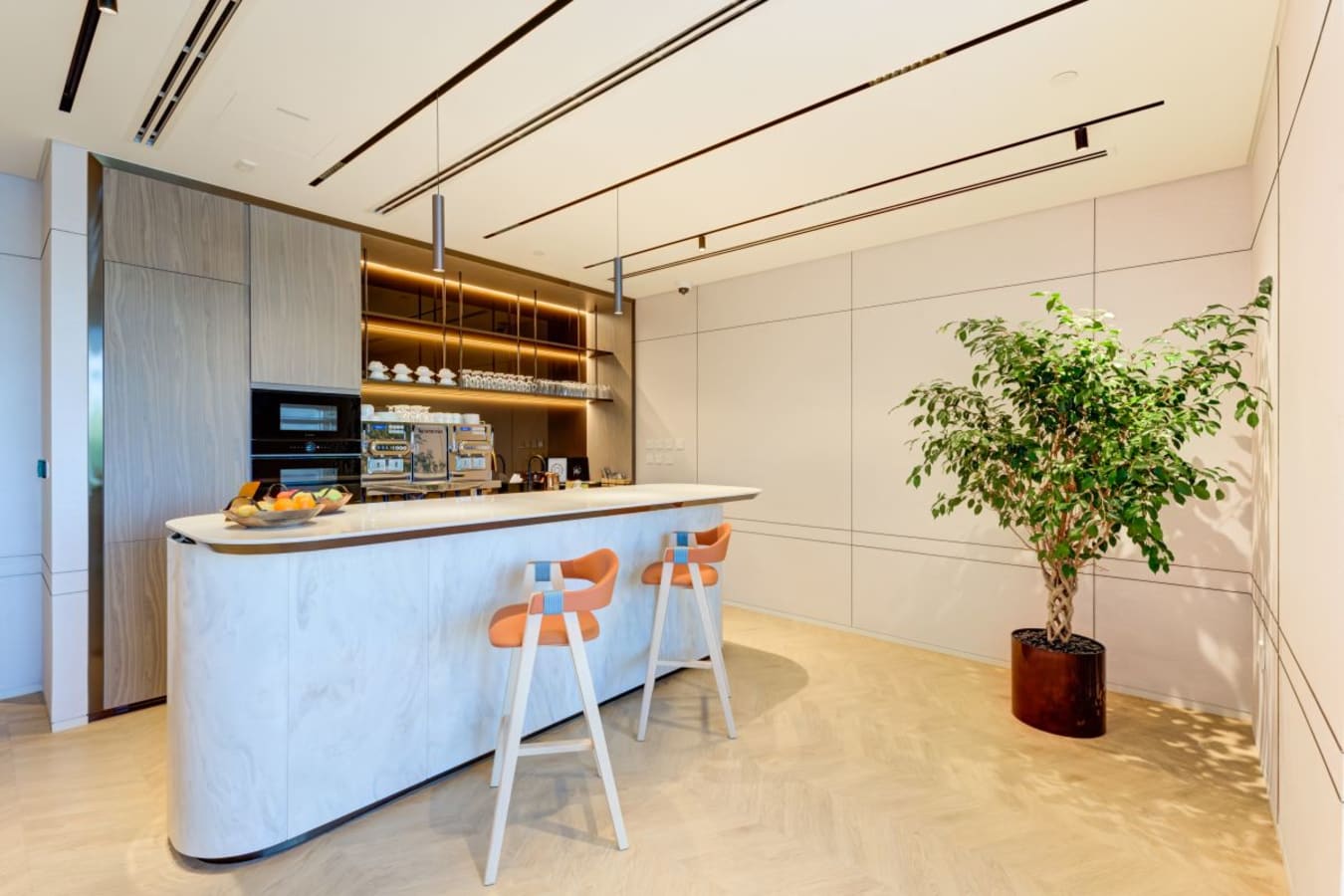 Modern kitchen area with sleek countertops, stylish bar stools, and lush greenery. Perfect for breaks!