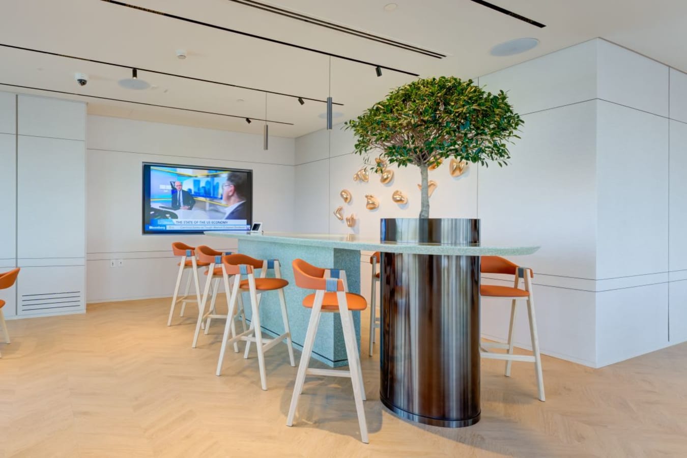 Modern coworking space with stylish seating, greenery, and a large TV for presentations.