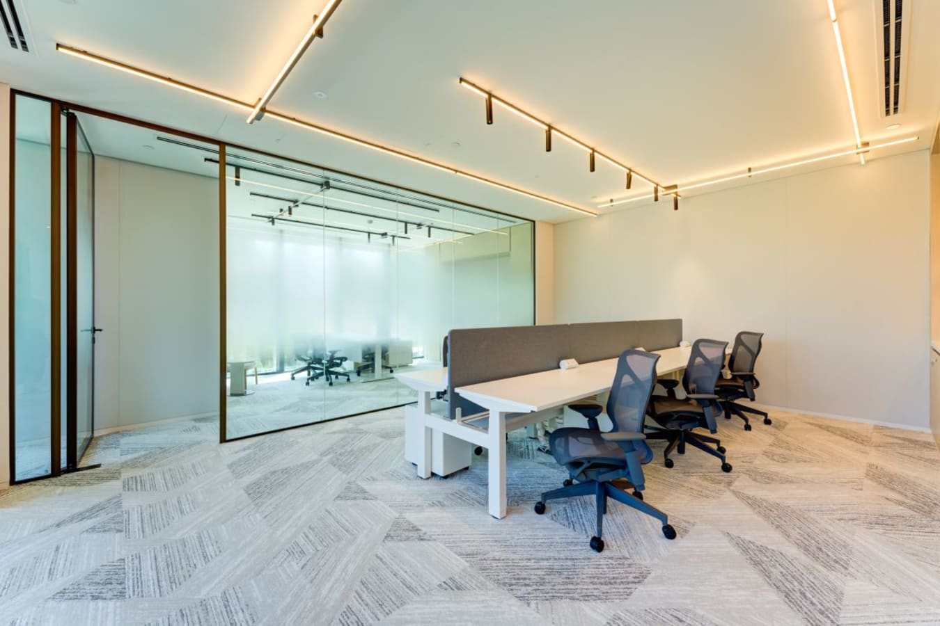 Modern coworking space with sleek desks, ergonomic chairs, and bright, ambient lighting. Ideal for collaboration.
