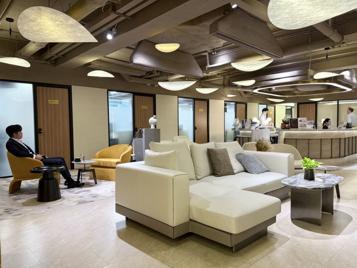 Modern coworking lounge with cozy seating, elegant lighting, and a stylish reception desk.