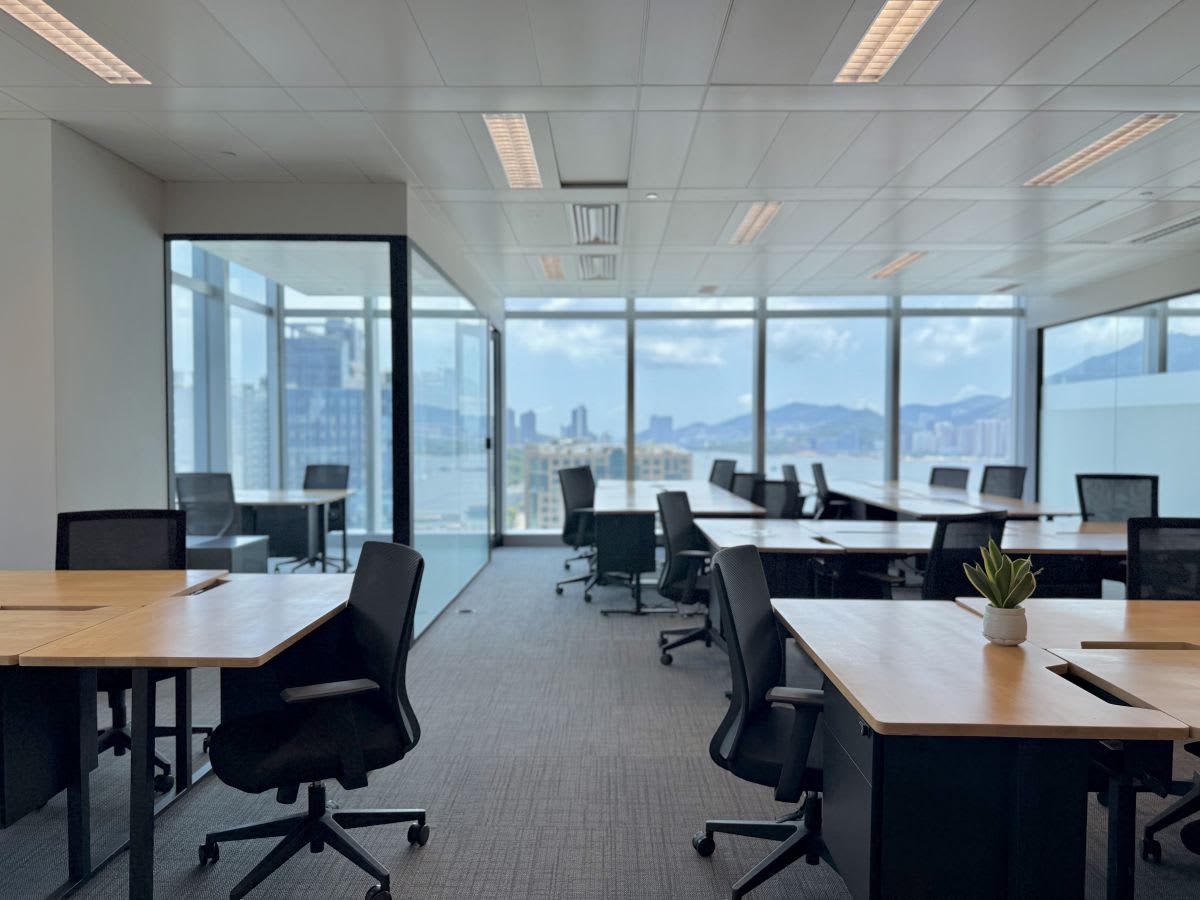 Modern coworking space with panoramic city views, abundant natural light, and sleek furnishings.