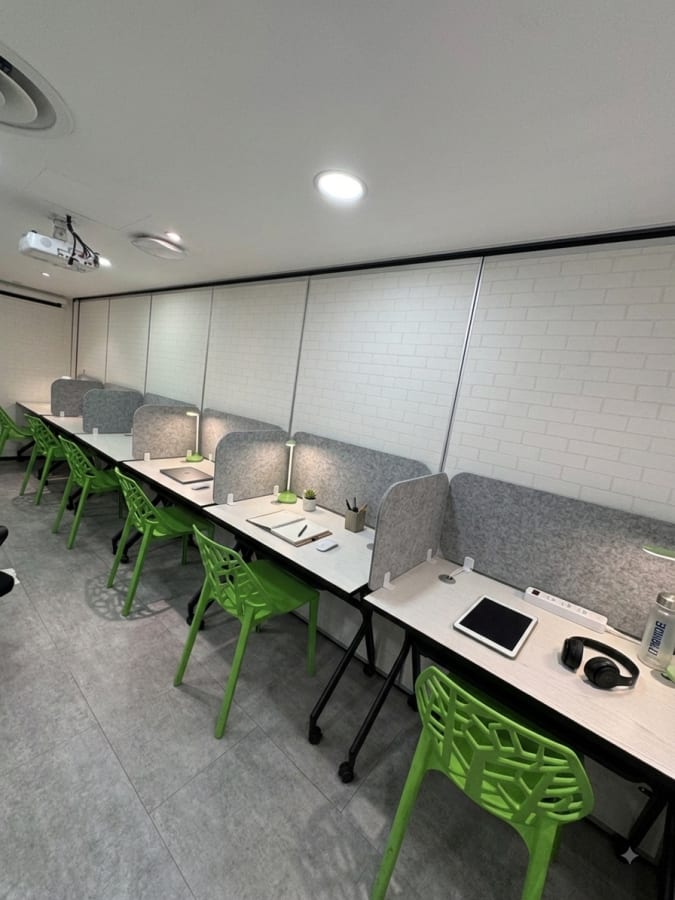 Modern coworking space with individual desks and vibrant green chairs. Ideal for focused work.