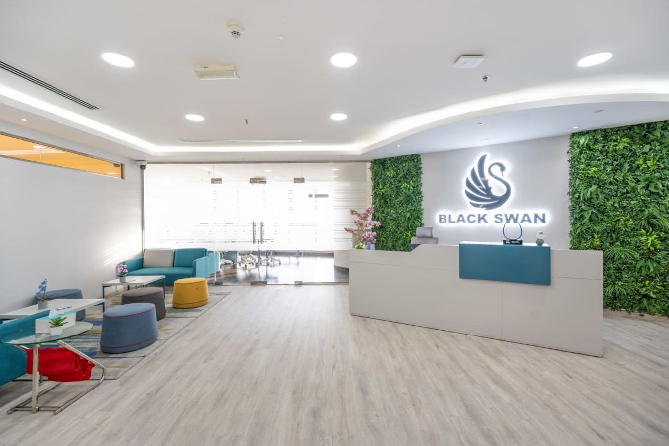 Modern coworking space with vibrant seating, lush greenery, and sleek reception in Business Bay.