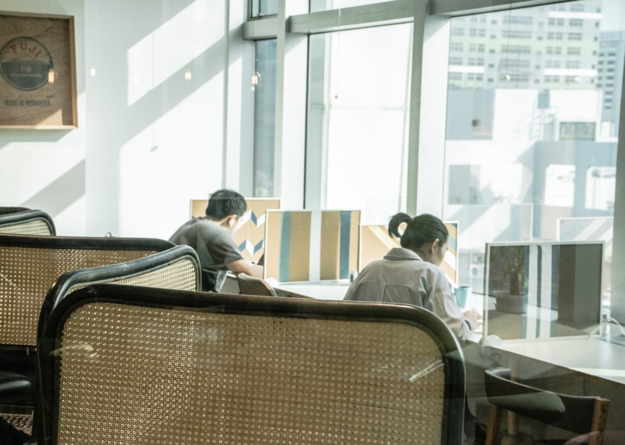Bright coworking space with ample seating and large windows overlooking the cityscape.
