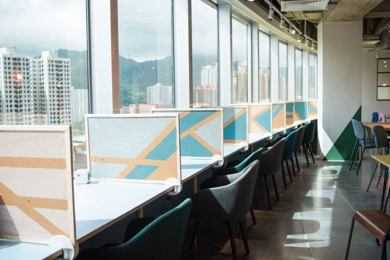 Modern coworking space with city views, bright natural light, and stylish workstations.