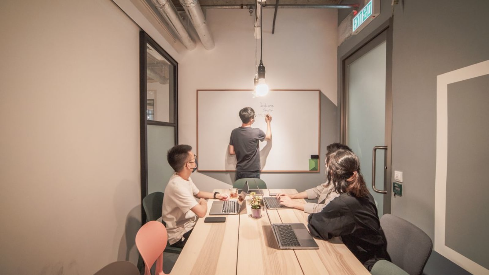Modern coworking space with collaborative table and whiteboard for creative meetings.