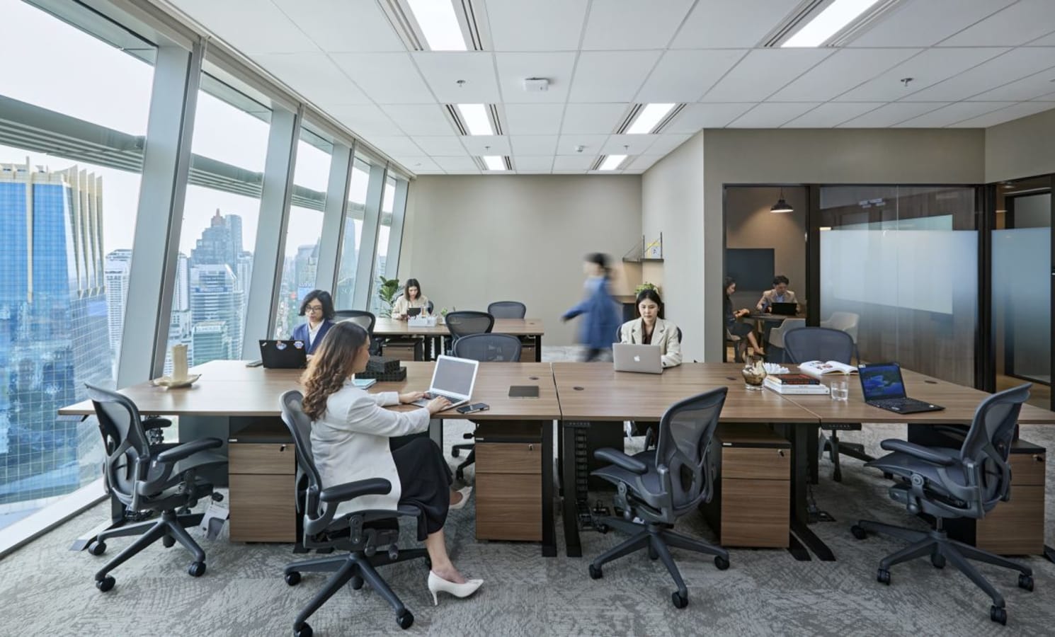 Modern coworking space with city views, ergonomic chairs, and collaborative workstations.