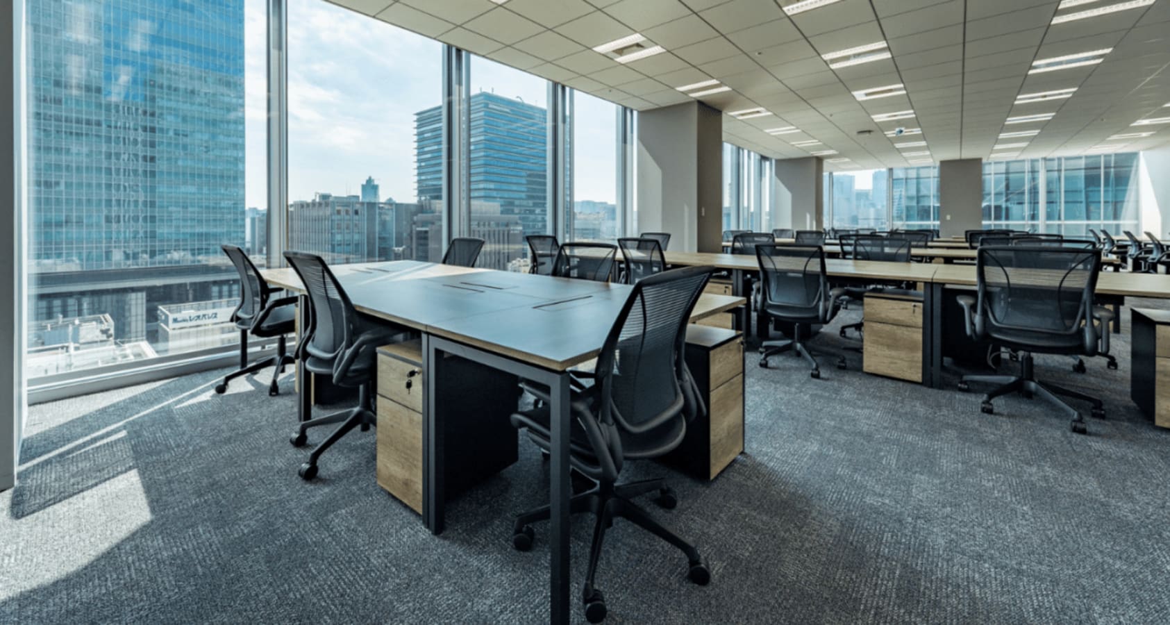 Spacious coworking area with panoramic city views and modern furnishings in Marunouchi, Tokyo.