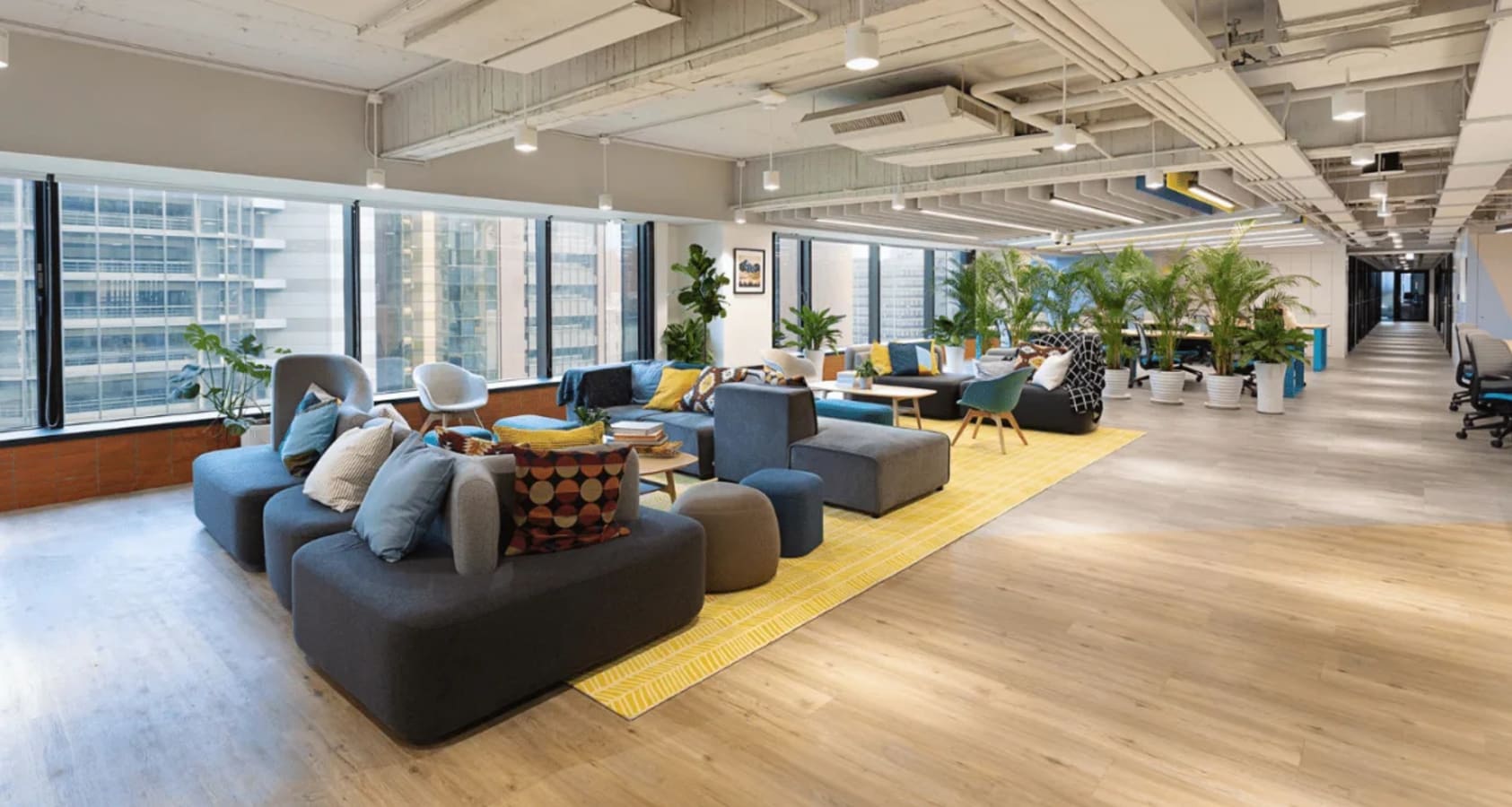 Bright, open coworking space in Taipei with modern seating, natural light, and lush greenery.