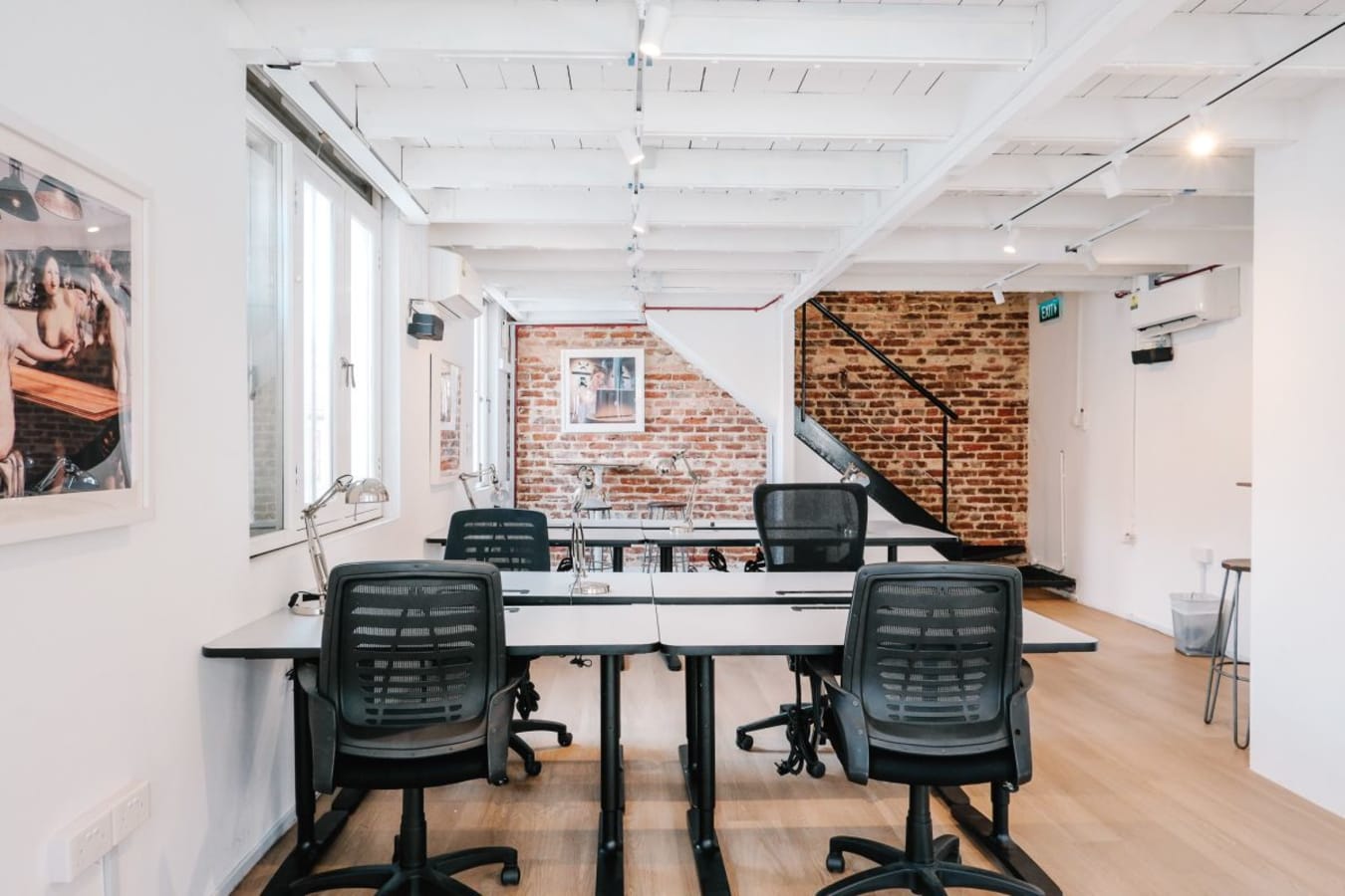 Bright coworking space with exposed brick, modern seating, and natural light. Perfect for productivity.