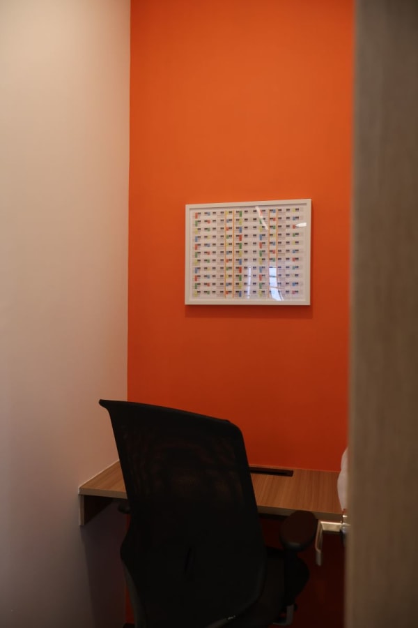 Cozy workspace with vibrant orange accent wall and ergonomic chair in Neil Road coworking space.