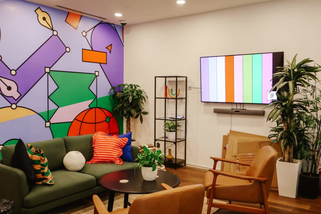 Vibrant coworking space with colorful art, cozy seating, and lush greenery. Ideal for creativity!