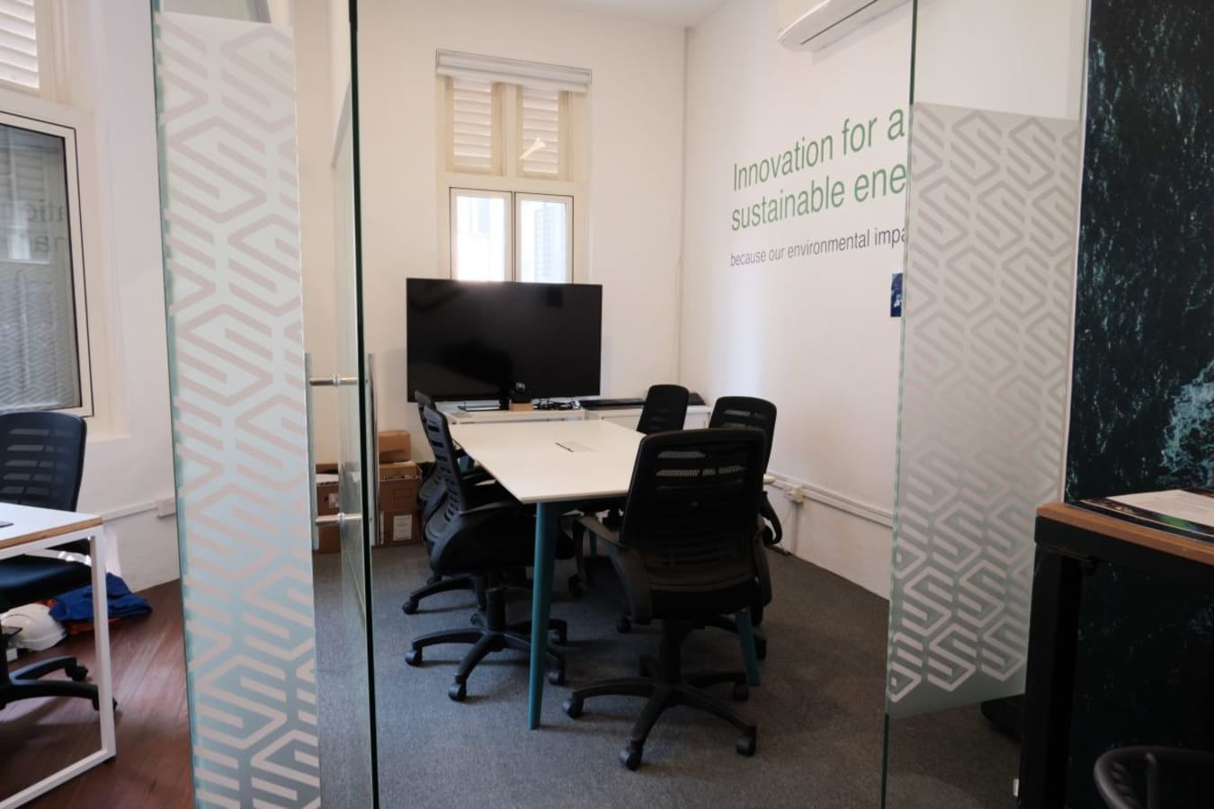 Modern coworking space with sleek meeting room, ergonomic chairs, and natural lighting.