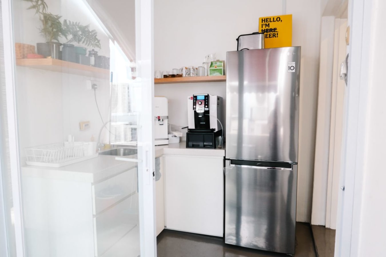 Modern kitchenette with sleek fridge and coffee machine, ideal for coworking breaks.