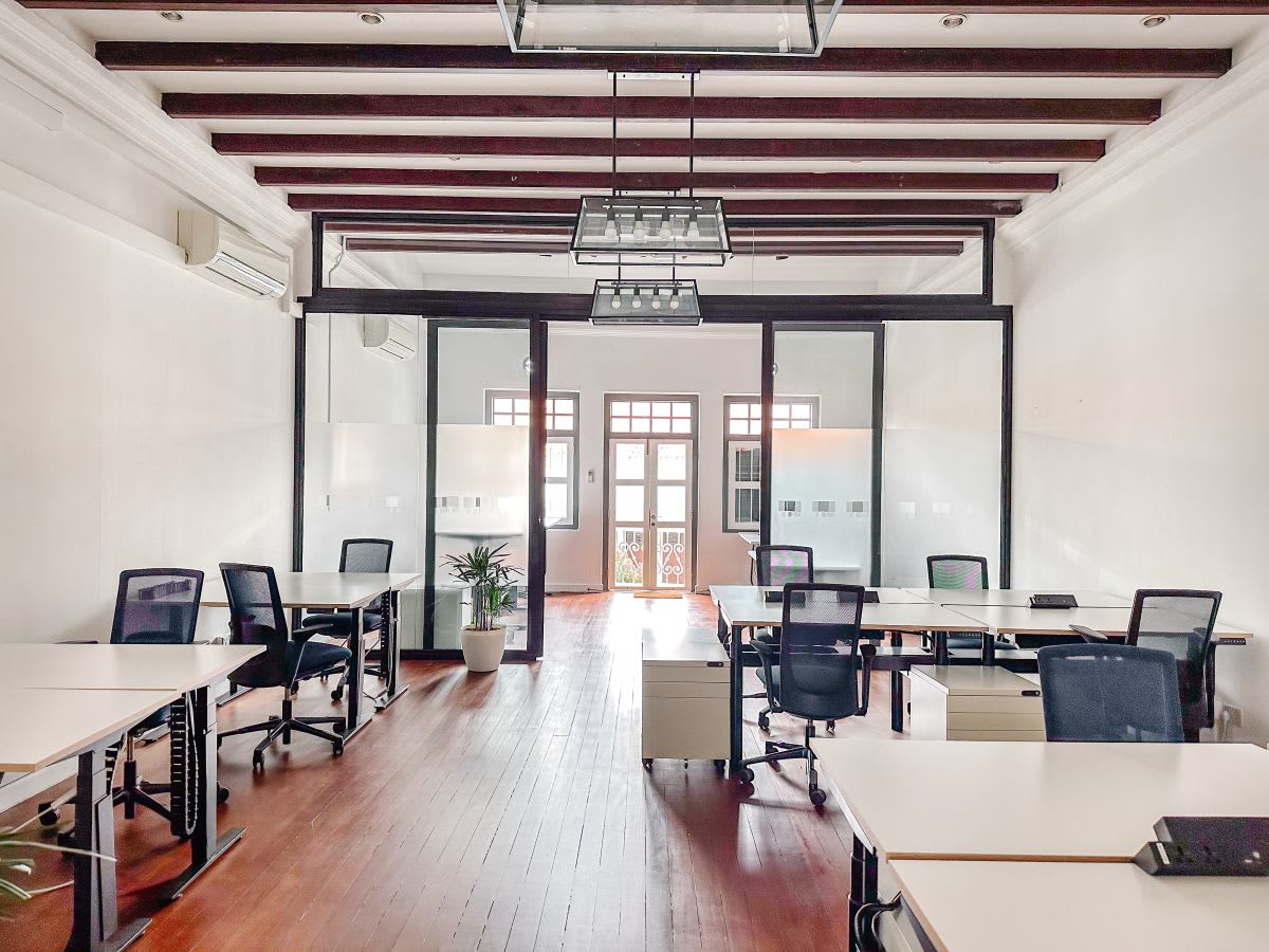 Modern coworking space with sleek desks, natural light, and elegant wooden beams.